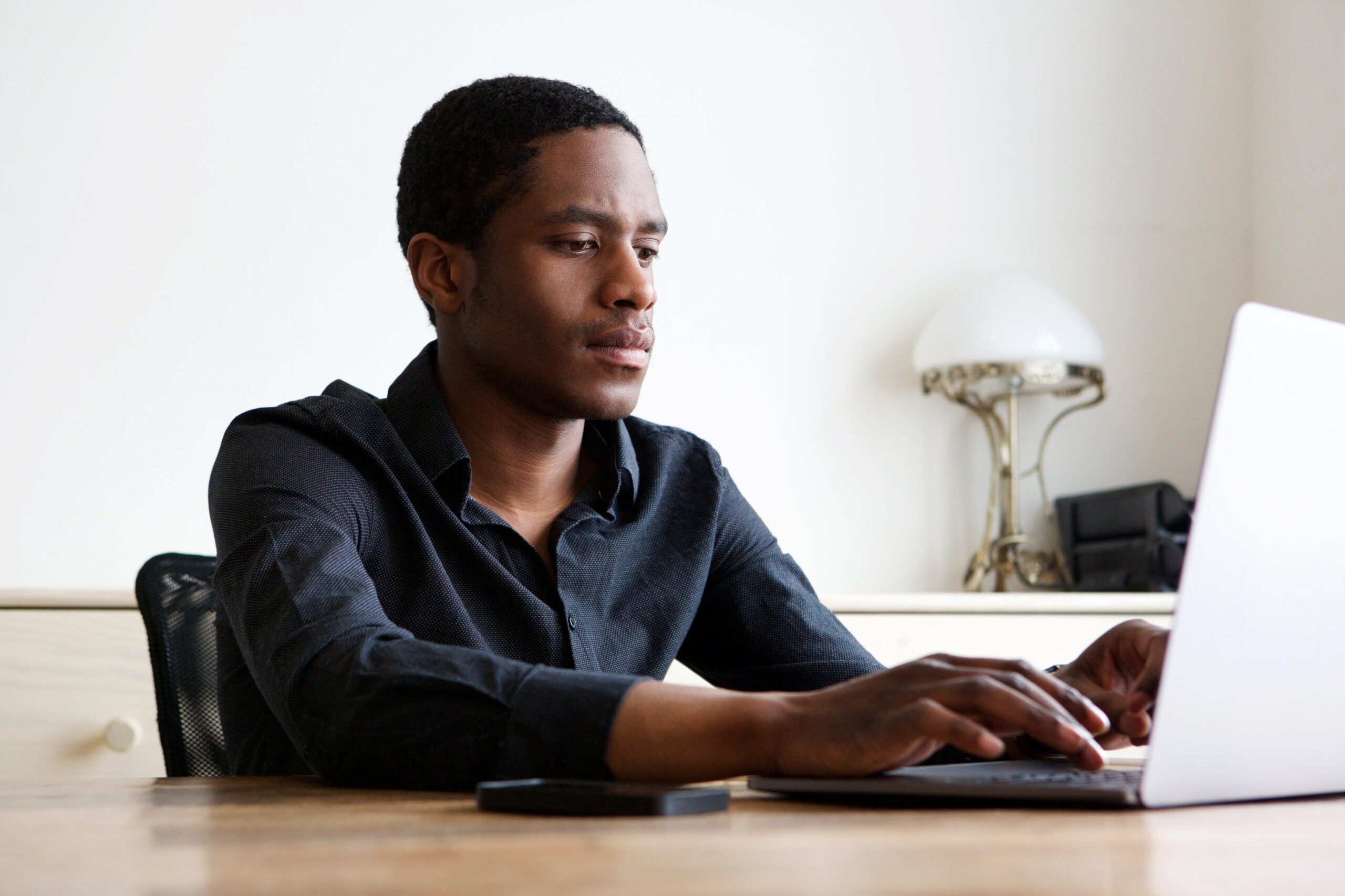 Portrait of young african american man working on laptop at home